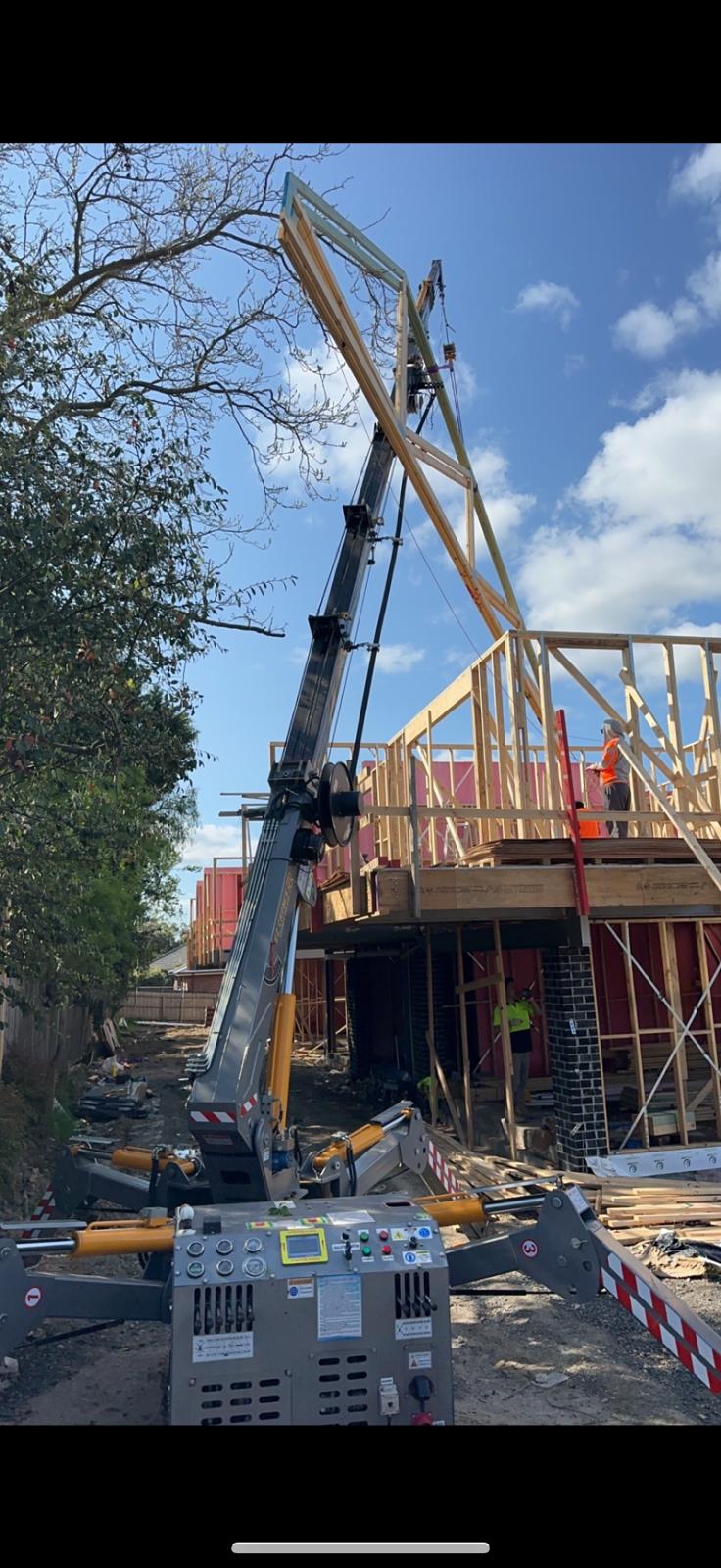 Spider crane lifting roof trusses at construction site